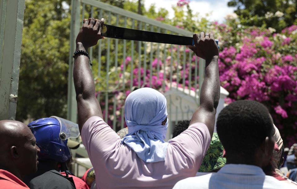 A protester holds up a machete as a symbol of self-defense against gangs, during a protest against insecurity in Port-au-Prince, Haiti, Friday, Aug. 25, 2023.