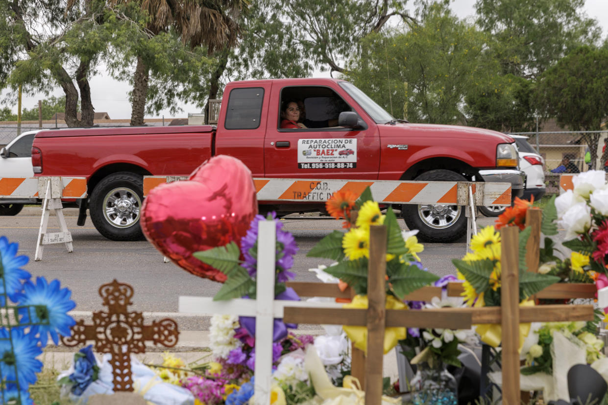 FILE - A passenger in a pickup truck looks at a memorial site, Monday, May 8, 2023, where eight migrants were killed and several others injured on Sunday, May 7, while waiting at a bus stop in Brownsville, Texas. Anger and guns, immigration turmoil, and political divisions about what democracy means are playing out across American Life in various ways. But in Texas, with its immense size and a population that grows by more than 1,000 people a day, the stage is far bigger — and often louder. (AP Photo/Michael Gonzalez, File)