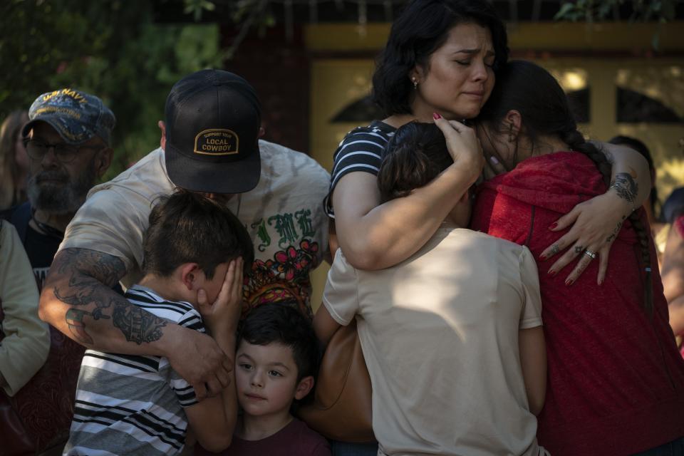 Raquel Martinez, comforts her two daughters while her husband, Daniel Martinez, comforts their sons outside Robb Elementary School, on Thursday, May 26, 2022, in Uvalde, Texas. Martinez and her four children stayed home for days, holding each other. They're scared, she said. Her two daughters, 15 and 11 years old, stood crying at a memorial. They'd both been taught by the two teachers who died, Irma Garcia and Eva Mireles. (AP Photo/Wong Maye-E)