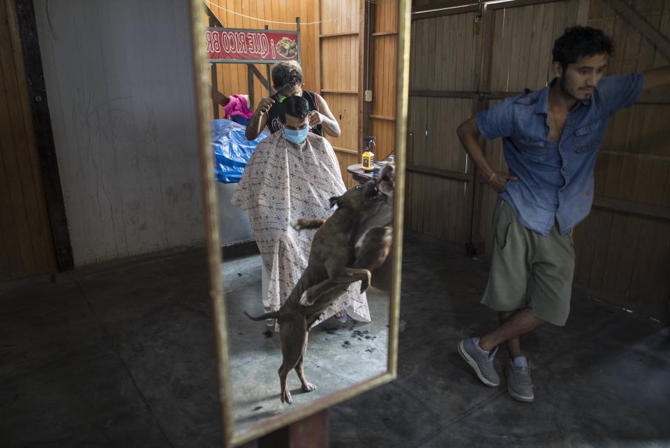 Estefano Godo, 19, cuts the hair of Alexander Placencia, 29, at his house due to the coronavirus emergency, in the outskirts of Lima, Peru, April 22, 2020. "Working inside my house with few clients it's the only way of earning some money to survive in this crisis," said Godo who's beauty salon has been forced to close. (AP Photo/Rodrigo Abd)