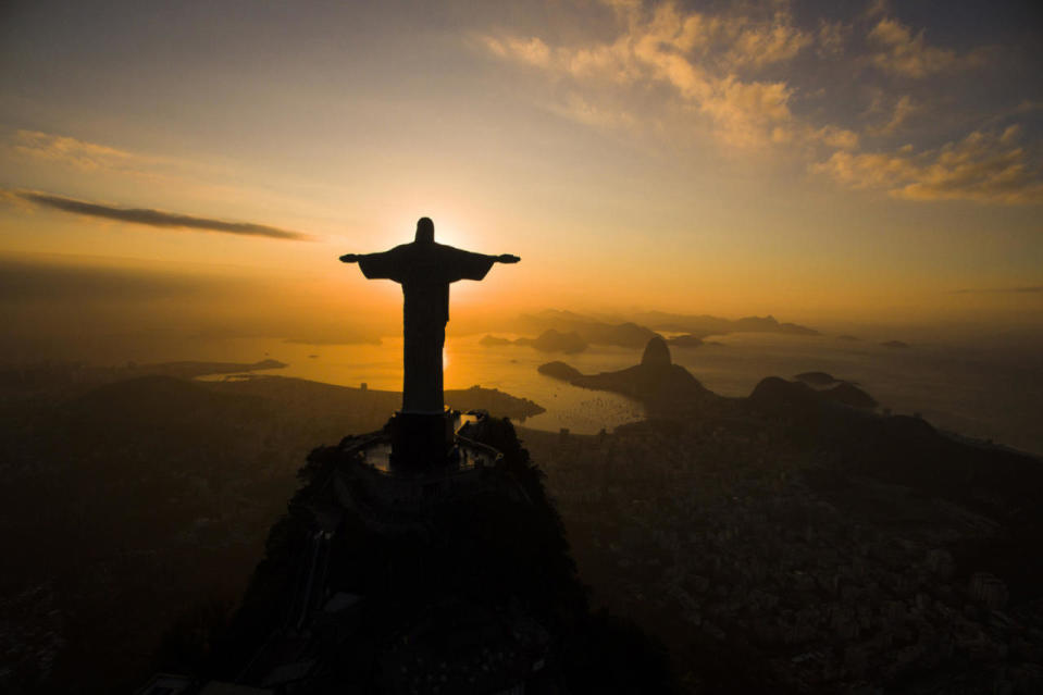 The sun rises behind the Christ the Redeemer statue
