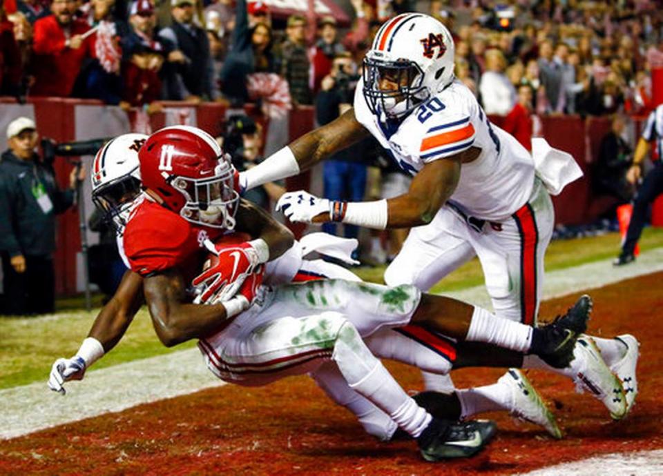 FILE - In this Nov. 24, 2018, file photo, Alabama wide receiver Henry Ruggs III (11) catches a pass for a touchdown as Auburn defensive back Roger McCreary (17) and linebacker Cameron Latu (20) defend during the second half of an NCAA college football game in Tuscaloosa, Ala. This year’s NFL draft features a superb group of wide receivers, including Ruggs, who are expected to make immediate impacts in the NFL.