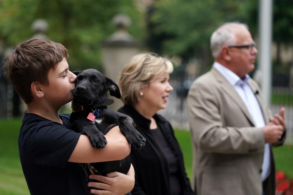 Gus Walz, left, holds Scout, a 3-month-old Labrador retriever the Walz family adopted, during a news conference with his parents to announce the family's newest addition at the governor's residence Thursday.