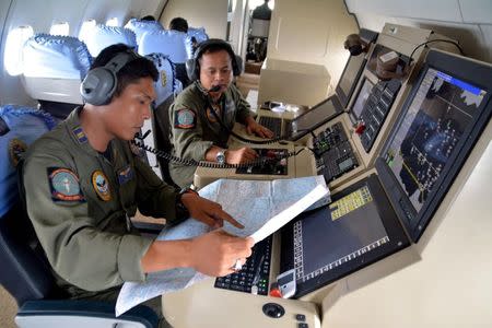 Two members of the Indonesian Navy's Tactical Commanding Operator (TACCO) help with the search for AirAsia flight QZ 8501 on board a CN235 aircraft over Karimun Java, in the Java Sea December 28, 2014 in this photo taken by Antara Foto. REUTERS/Antara Foto/Eric Ireng