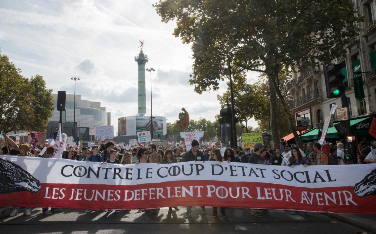 Protestors march behind a banner reading