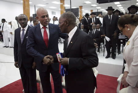 Haiti's outgoing President Michel Martelly (2L) shakes hands with the Senate President Jocelerme Privert (C) in presence of the Prime Minister Evans Paul during a ceremony marking the end of Martelly's presidential term, in the Haitian Parliament in Port-au-Prince, Haiti, February 7, 2016. REUTERS/Andres Martinez Casares