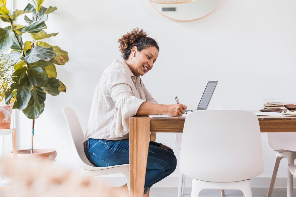 The mid adult business woman smiles as she works from home.