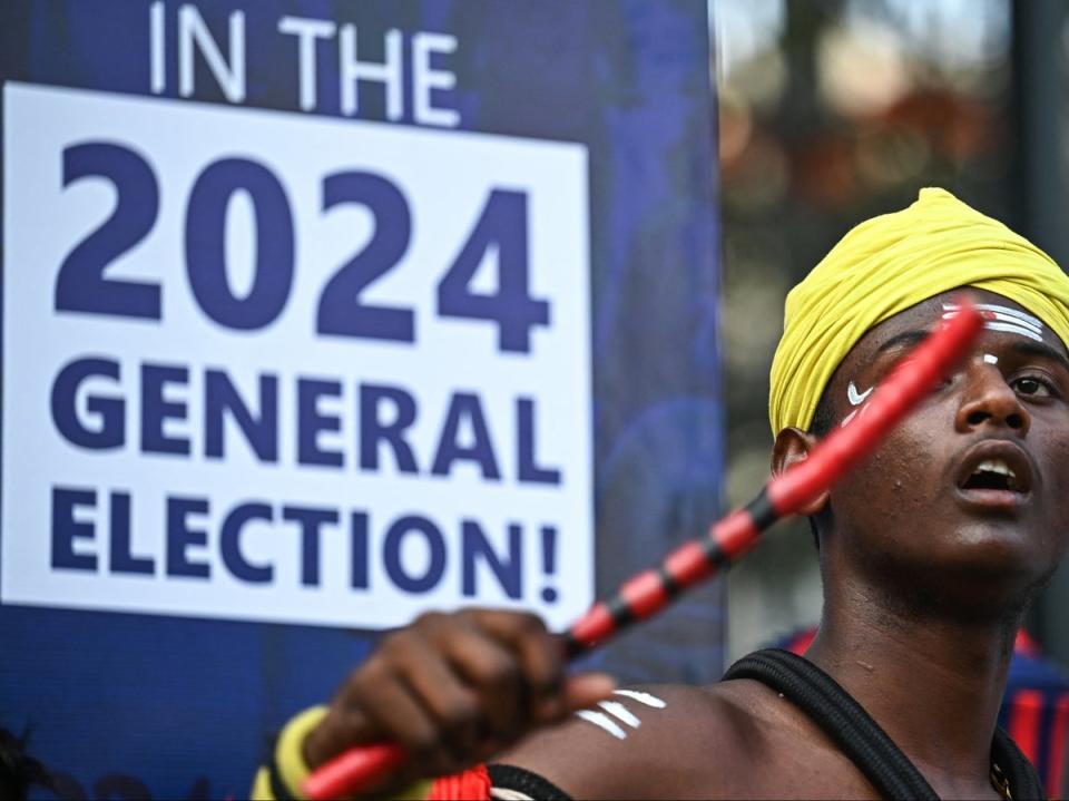 An artist dressed in a traditional attire performs in front of an election sign board during the Vote-A-Thon, an awareness campaign organized by the Karnataka’s Chief Electoral Office to encourage 100 percent voting turnout for the upcoming 2024 general elections, in Bengaluru on 17 March 2024 (AFP via Getty Images)