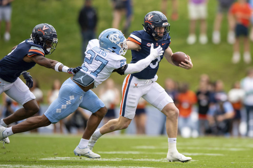 Virginia quarterback Brennan Armstrong (5) stiff-arms North Carolina defensive back Giovanni Biggers (27) during the first half of an NCAA college football game on Saturday, Nov. 5, 2022, in Charlottesville, Va. (AP Photo/Mike Caudill)