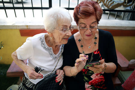 Holocaust survivors look at the mobile phone after they arrived to take part in the annual Holocaust survivors' beauty pageant in Haifa, Israel October 14, 2018. REUTERS/Corinna Kern