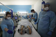 FILE - In this Wednesday, Jan. 27, 2021 file photo, Critical Care staff look after a COVID-19 patient on the Christine Brown ward at King's College Hospital in London. The scale of Britain's coronavirus outbreak can seem overwhelming, with tens of thousands of new infections and more than 1,000 deaths added each day. But on hospitals' COVID-19 wards, the pandemic feels both epic and intimate, as staff fight the virus one patient at a time, and with no end in sight. (AP Photo/Kirsty Wigglesworth, Pool, File)