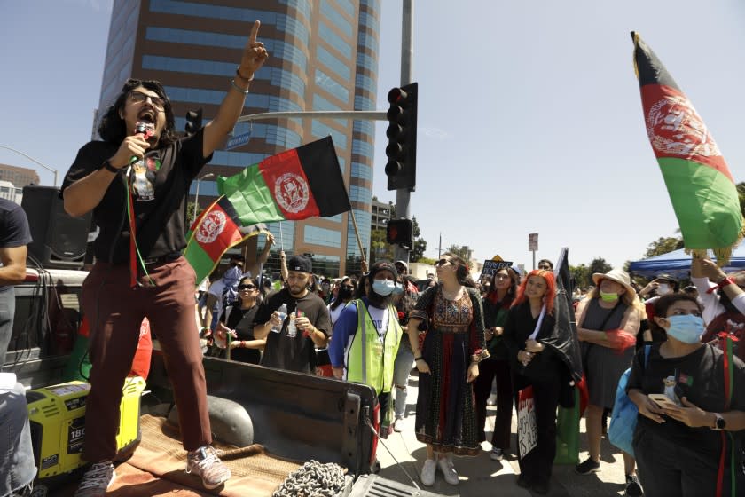 LOS ANGELES, CA - AUGUST 28, 2021 - Afghan American activist Arash Azizzada, left, speaks to the crowd of hundreds of Afghan-Americans and others in support of Afghanistan and the hope that President Biden will step-up efforts to evacuate Afghans and to send humanitarian aid to the country outside the Federal Building in Los Angeles on August 28, 2021. Azizzada, who lives in South L.A., has been using his laptop and his phone from a home office to help organize and promote protests, consult Afghans who are trying to escape, and to raise awareness of bureaucratic hurdles that evacuees face. in Westwood on August 28, 2021. (Genaro Molina / Los Angeles Times)