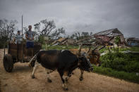 Men lead their ox cart past a tobacco warehouse smashed by Hurricane Ian in Pinar del Rio, Cuba, Tuesday, Sept. 27, 2022. Hurricane Ian tore into western Cuba as a major hurricane and left 1 million people without electricity, then churned on a collision course with Florida over warm Gulf waters amid expectations it would strengthen into a catastrophic Category 4 storm. (AP Photo/Ramon Espinosa)
