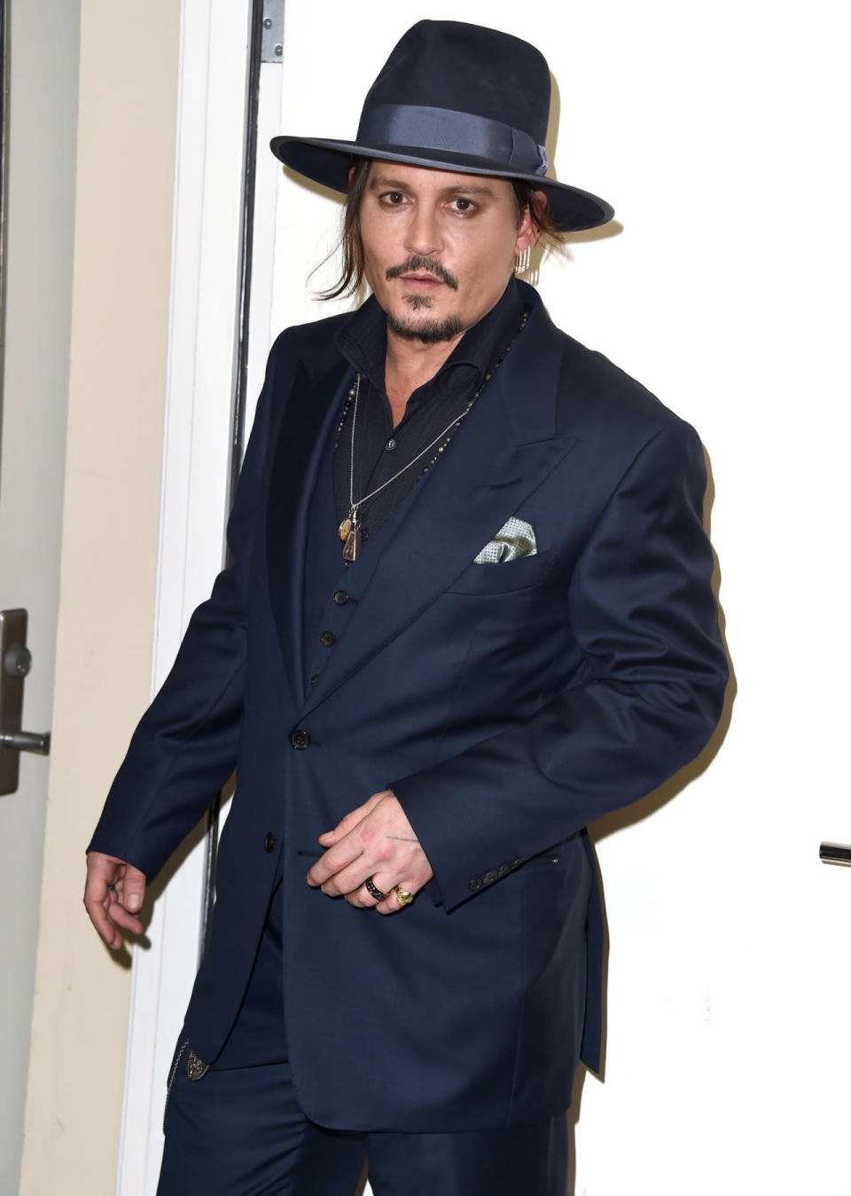 Johnny Depp in a navy blue three-piece suit and a fedora at the 19th Annual Hollywood Film Awards in Beverly Hills, California.