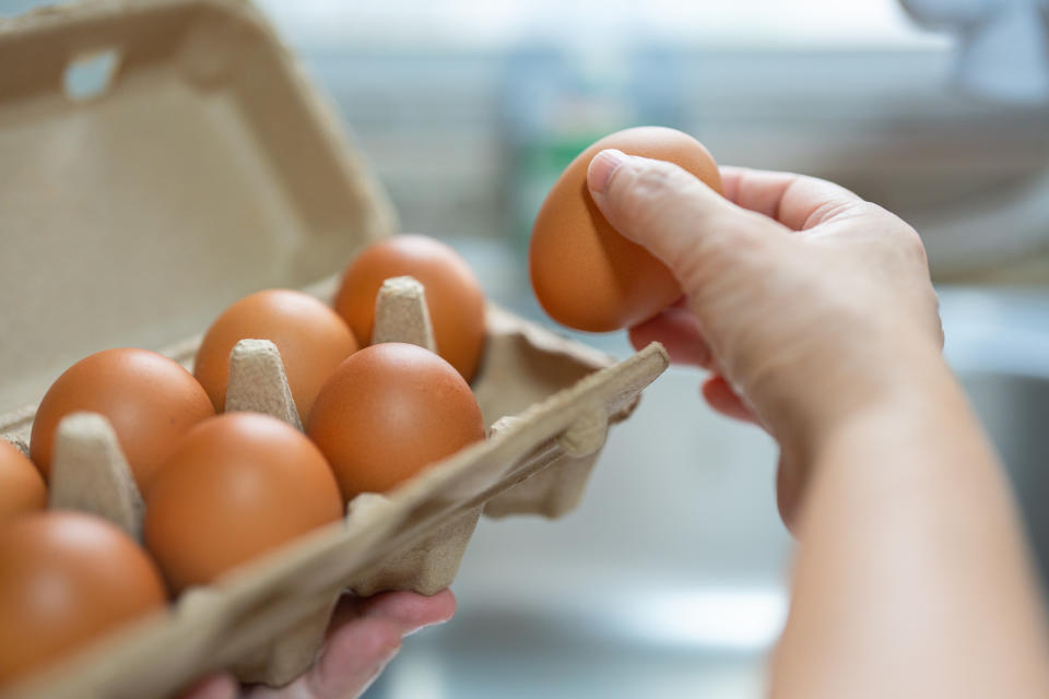 someone taking an egg out of a carton