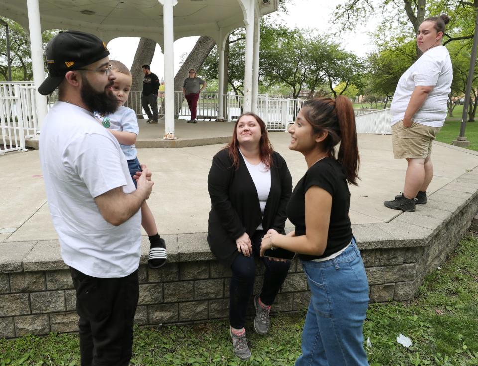 Cory Copeland holds his son Jaydyn, 2, as he talks with other former foster children of Jennifer Wokojance (not pictured), Jeanna Birbrayer  (seated), Miaya, 17, and Allyson Hamrick, at the gazebo at Lake Anna in Barberton. Hamrick's twin brother, Aaron, who was also a former foster child, and his girlfriend Kate Hillyer are in the background.