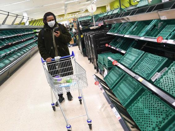 A shopper passes empty shelves at a Tesco supermarket in London (EPA)