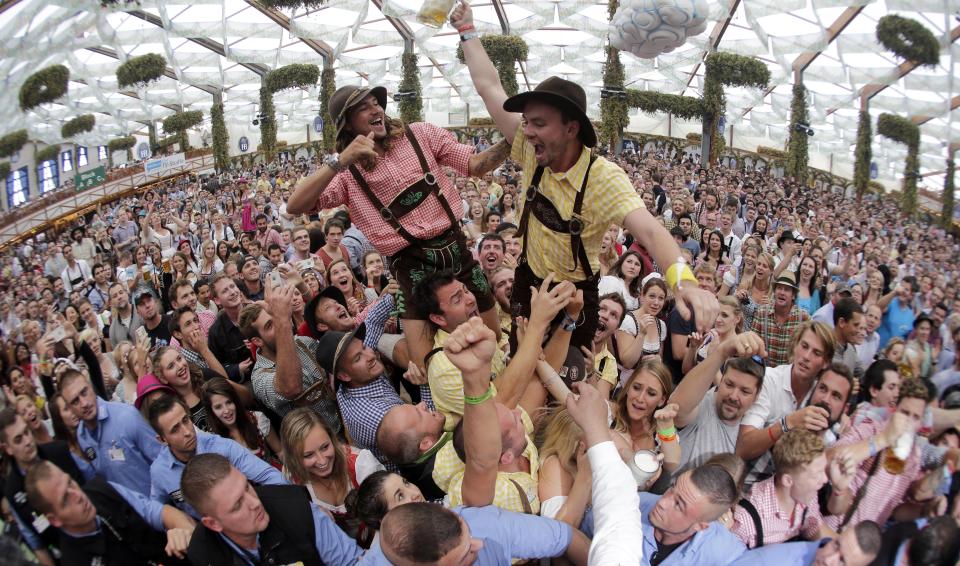 In this Saturday, Sept. 20, 2014 file photo people celebrate the opening of the 181th Oktoberfest beer festival in Munich, southern Germany. Bavarian head of state Markus Soeder and Munich mayor Dieter Reiter will hold a news conference on Tuesday, April 21, 2020, about this year's October party after the coronavirus outbreak. (AP Photo/Matthias Schrader, File)