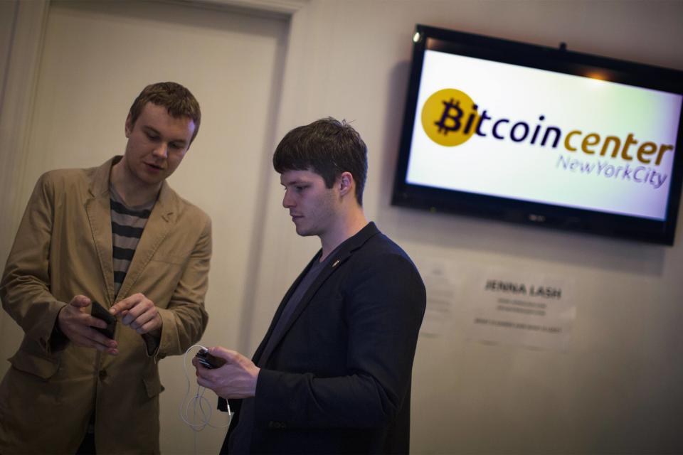 Austin Alexander, deputy director of Bitcoin Center New York City (R) talks about his digital wallet with an attendee during the Satoshi Square at the Bitcoin Center NYC. (Reuters.) 