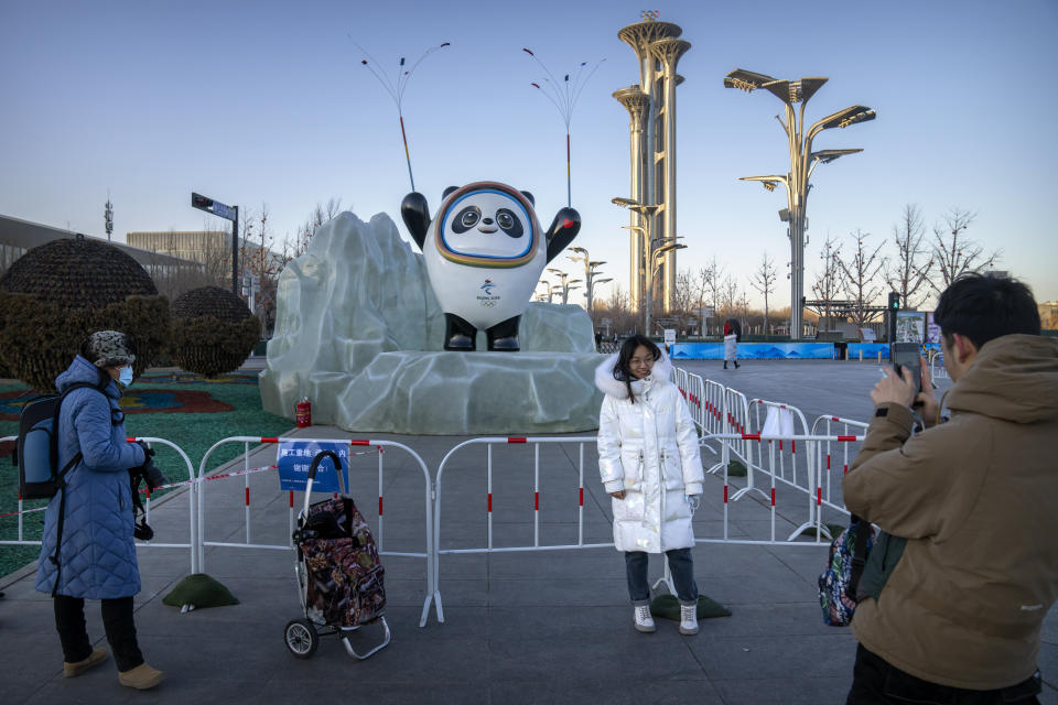 A woman poses for a photo with a statue of the Winter Olympics mascot Bing Dwen Dwen in Beijing, Jan. 12, 2022. (AP Photo/Mark Schiefelbein)