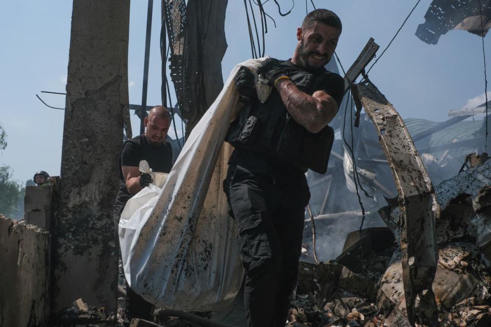 Ukrainian first responders transport a body of a civilian killed in a Russian missile attack on a publishing factory in Kharkiv, Ukraine, on May 23, 2024. (Francis Farrell/The Kyiv Independent)