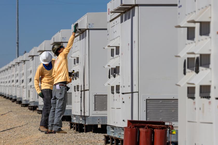 DAGGETT, CA - OCTOBER 18: Rafael Carvajal Jr., 18, left, and Rafael Carvajal, 40, Wartsila technicians check equipment installed at Clearway Daggett 3 Solar Power + Battery Energy Storage System on Wednesday, Oct. 18, 2023 in Daggett, CA. (Irfan Khan / Los Angeles Times)