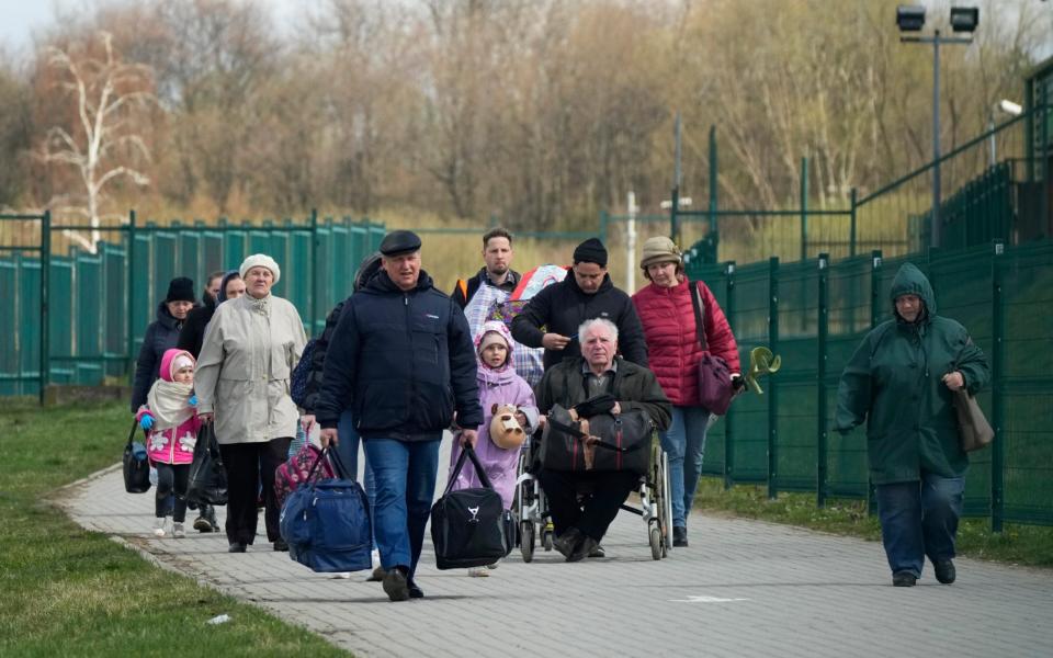 Refugees walk after fleeing war in Ukraine at the border crossing in Medyka, southeastern Poland, Monday, April 11, 2022. - Sergei Grits/AP