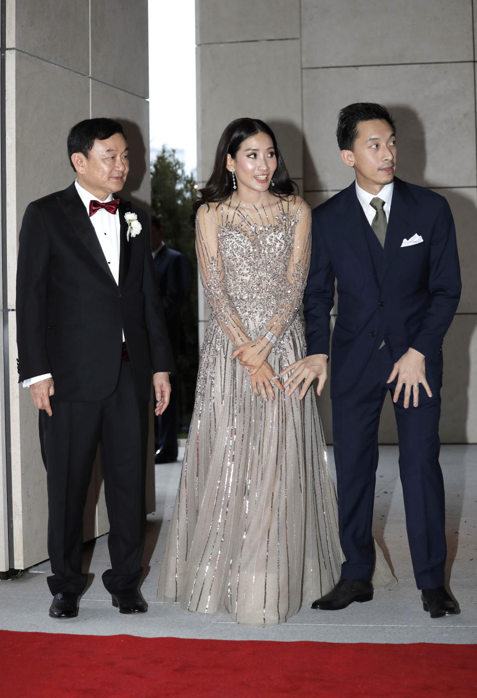 From left, former Thai Prime Minister Thaksin Shinawatra, his daughter Pintongtha "Aim" and her hnusband Nattapong "Pong" Kunakornwong wait for their guests at a hotel in Hong Kong, Friday, March 22, 2019. (AP Photo/Kin Cheung)