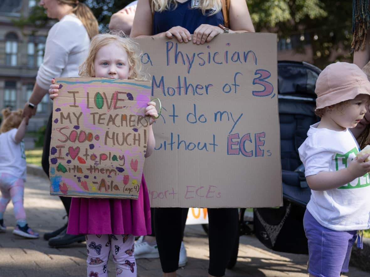A mother and her 4-year-old daughter hold signs in support of early childhood educators at a day of action Thursday in downtown Halifax.   (CBC/Robert Short - image credit)