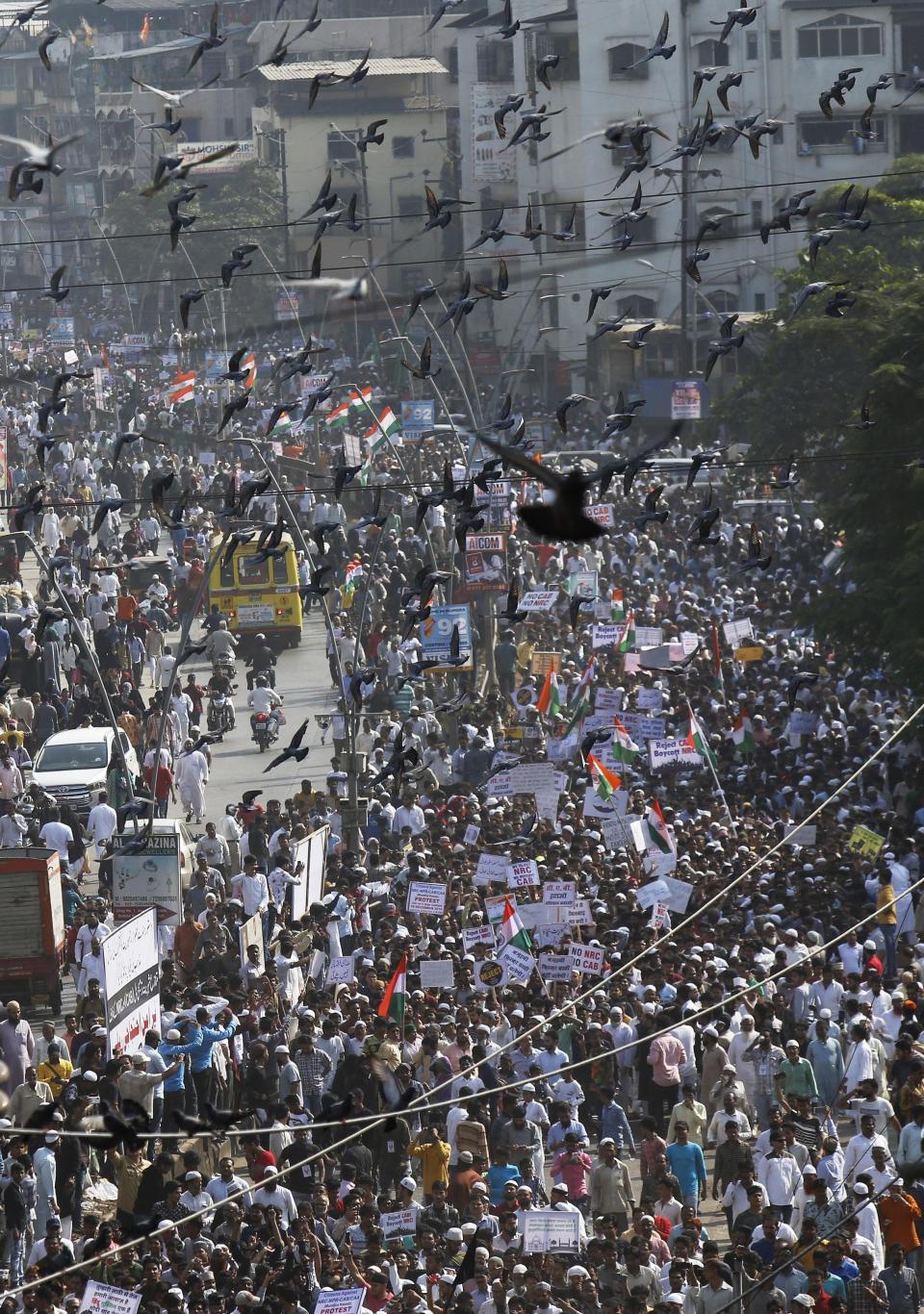 Pigeons fly past as Indians march during a protest against the Citizenship Act in Mumbai, India, Wednesday, Dec. 18, 2019. India's Supreme Court on Wednesday postponed hearing pleas challenging the constitutionality of the new citizenship law that has sparked opposition and massive protests across the country. (AP Photo/Rajanish Kakade)