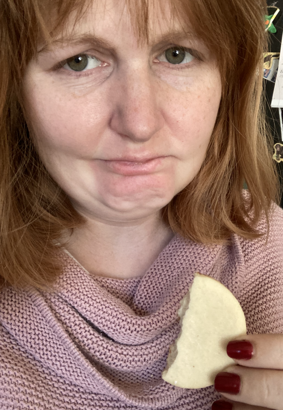 author holding the cookie and frowning at the camera