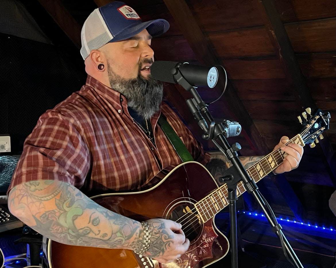 Aaron Hymes, at the microphone, rehearses recently with his band at his Paris Township home. Hymes is an award-winning country Christian music artist who recently signed a Nashville-based recording contract.