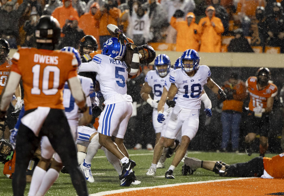 Oklahoma State running back Ollie Gordon II (0) dives over BYU cornerback Eddie Heckard (5) for a touchdown during the second overtime in an NCAA college football game Saturday, Nov. 25, 2023, in Stillwater, Okla. (AP Photo/Mitch Alcala)