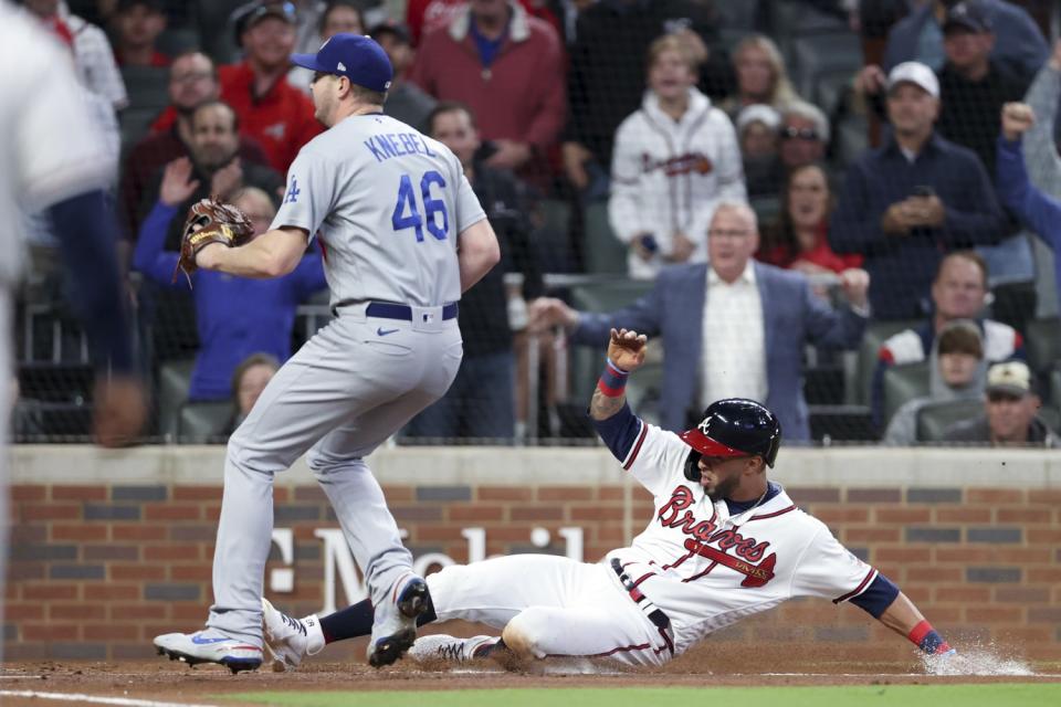 Atlanta, GA - October 16: Atlanta Braves' Eddie Rosario, right, slides into home to score off a wild pitch.