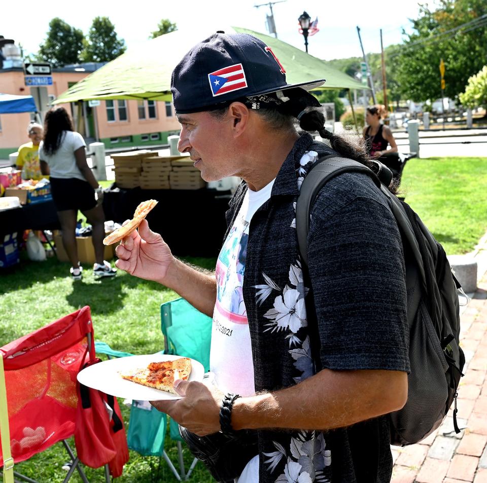 Tomas Medina, a Framingham man with an insecure housing situation, enjoys free pizza during a "Neighborhood Give Back" event on the Framingham Downtown Common, Sept. 3, 2022.