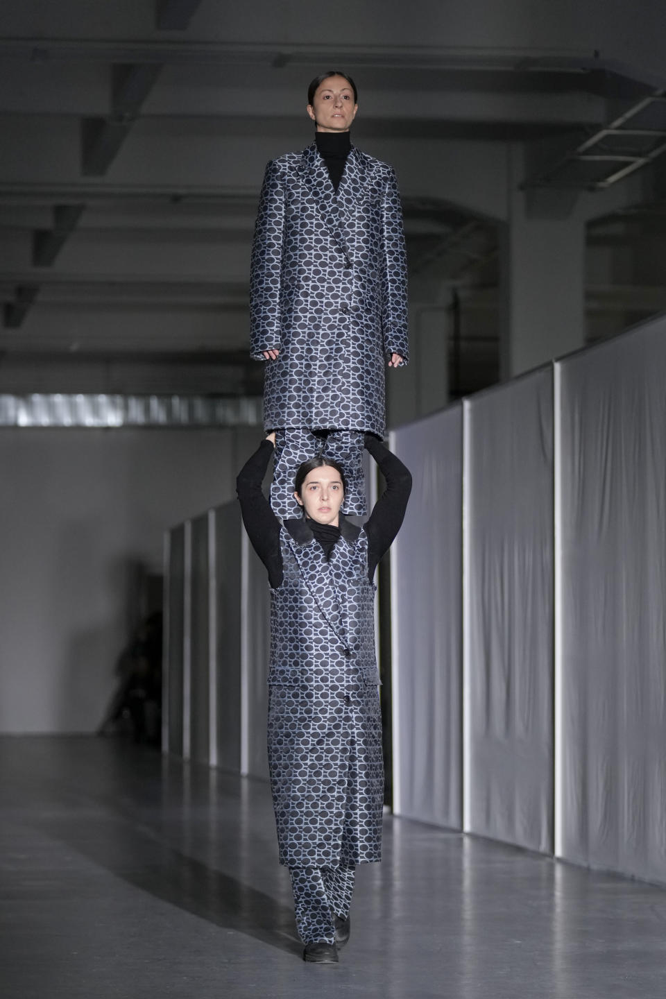 A model balances on top of another model wearing creations as part of the men's Federico Cina Fall-Winter 2024-2025 collection, that was presented in Milan, Italy, Saturday, Jan. 13, 2024. (AP Photo/Antonio Calanni).