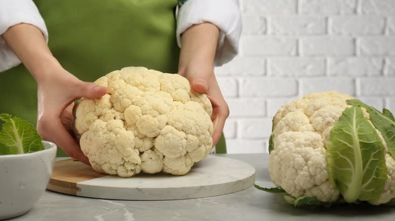 Person placing cauliflower on cutting board