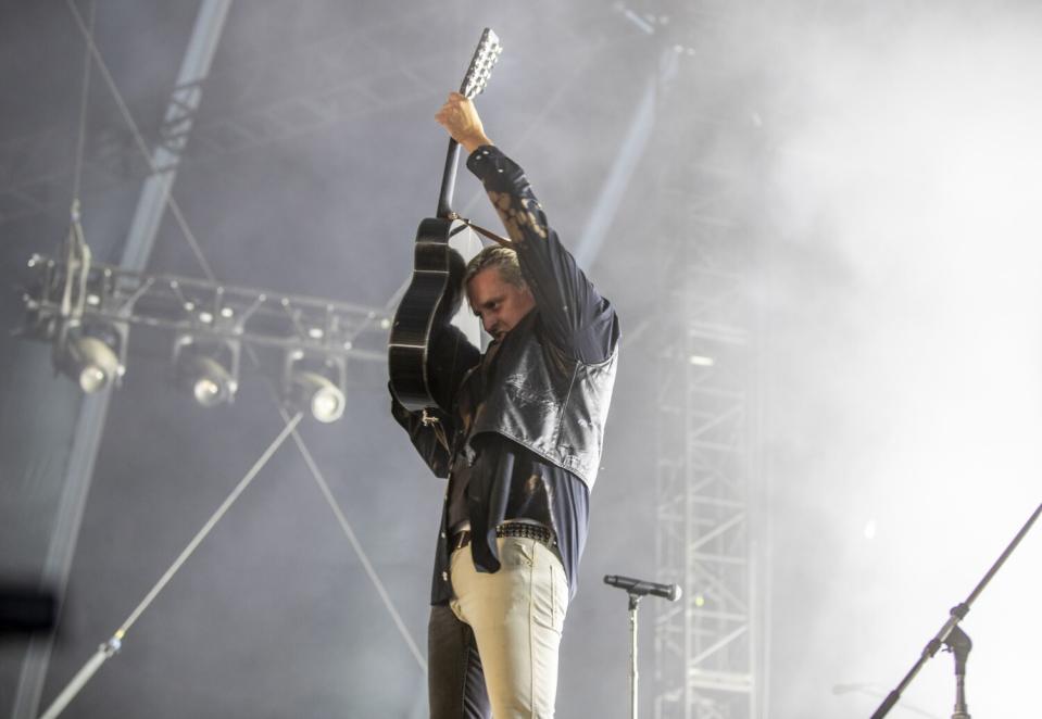 A man holds up his guitar on stage.