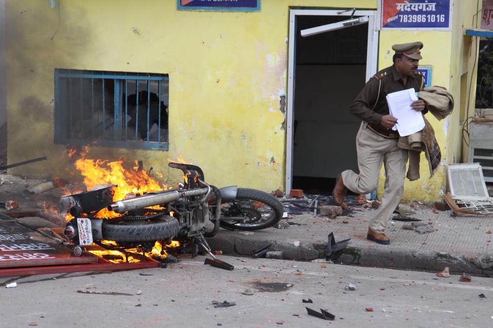 TOPSHOT - In this photo taken on December 19, 2019 an officer runs with documents from a police post damaged by protesters during a demonstration against India's new citizenship law in Lucknow. - Indians defied bans on assembly on December 19 in cities nationwide as anger swells against a citizenship law seen as discriminatory against Muslims, following days of protests, clashes and riots that have left six dead. (Photo by STR / AFP) (Photo by STR/AFP via Getty Images)