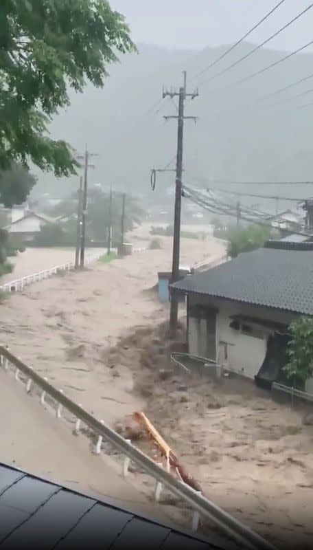 Muddy water flows through a residential area near Kuma river in Ashikita