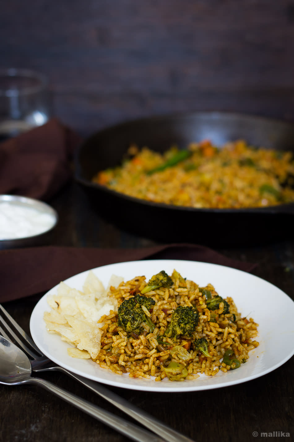 <p>A very popular street food in Mumbai, this dish is prepared on a tawa (griddle). The dish includes boiled vegetables like potatoes, beans, carrots, cauliflower and capsicum. The most important ingredient in this preparation is the Pav Bhaji Masala. Tawa pulao is fairly simple to cook at home and makes for a very healthy and a delicious meal. Heat oil in a non-stick pan. Add cumin seeds and onions. Saute till onions turn brown. Add ginger and garlic paste, tomatoes and cook till tomatoes become soft. To this add green peas, chopped carrot, pav bhaji masala, red chilli powder and a little water. Mix well and cook for two to three minutes. Add precooked rice and mix again. Add salt, coriander leaves, a dash of lemon juice and stir. Cook for sometime and a fabulous dish is ready to be served. “Creative Commons Tawa Pulao” by Mallika Bhat is licensed under CC BY 2.0 </p>