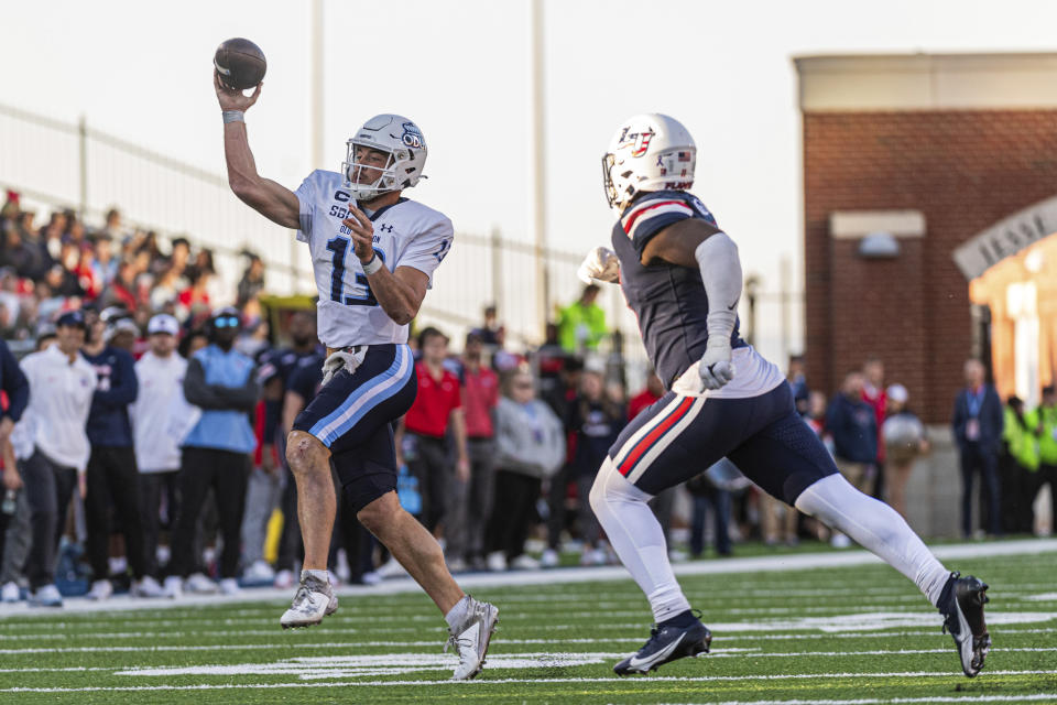 Old Dominion's Grant Wilson (13) passes downfield while Liberty's CJ Bazile, Jr. rushes during the second half an NCAA college football game, Saturday, Nov. 11, 2023, in Lynchburg, Va. (AP Photo/Robert Simmons)