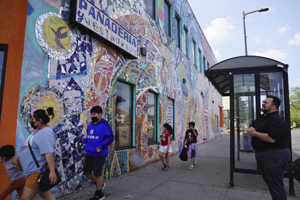 The Rev. Hierald Osorto of St. Paul Lutheran Church, right, talks about a community mural on Lake Street in Minneapolis on Thursday, May 12, 2022. Osorto, whose parish is near the Abubakar As-Saddique Islamic Center, does not anticipate pushback from his congregants on the public broadcasting of the Islamic call to prayer. (AP Photo/Jessie Wardarski)