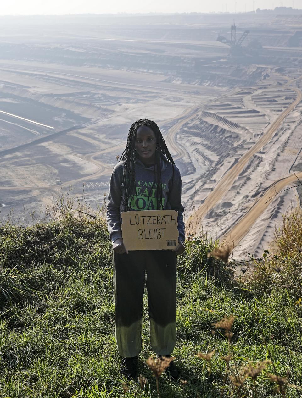 Climate activist Vanessa Nakate from Uganda holds a sign that reads: "Luetzerath stays" during a visit to the Garzweiler open-cast coal mine in Luetzerath, western Germany, Saturday, Oct. 9, 2021. The village of Luetzerath, now almost entirely abandoned as the mine draws ever closer, will be the latest village to disappear as coal mining at the Garzweiler mine expands. Garzweiler, operated by utility giant RWE, has become a focus of protests by people who want Germany to stop extracting and burning coal as soon as possible. (AP Photo/Martin Meissner)