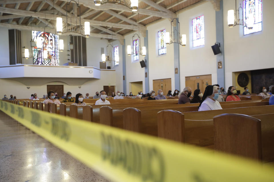 Yellow caution tape is viewed during a service at the San Gabriel Mission, Sunday, July 12, 2020, in San Gabriel, Calif. A fire on Saturday destroyed the rooftop and most of the interior of the nearly 250-year-old California church that was undergoing renovation. (AP Photo/Marcio Jose Sanchez)