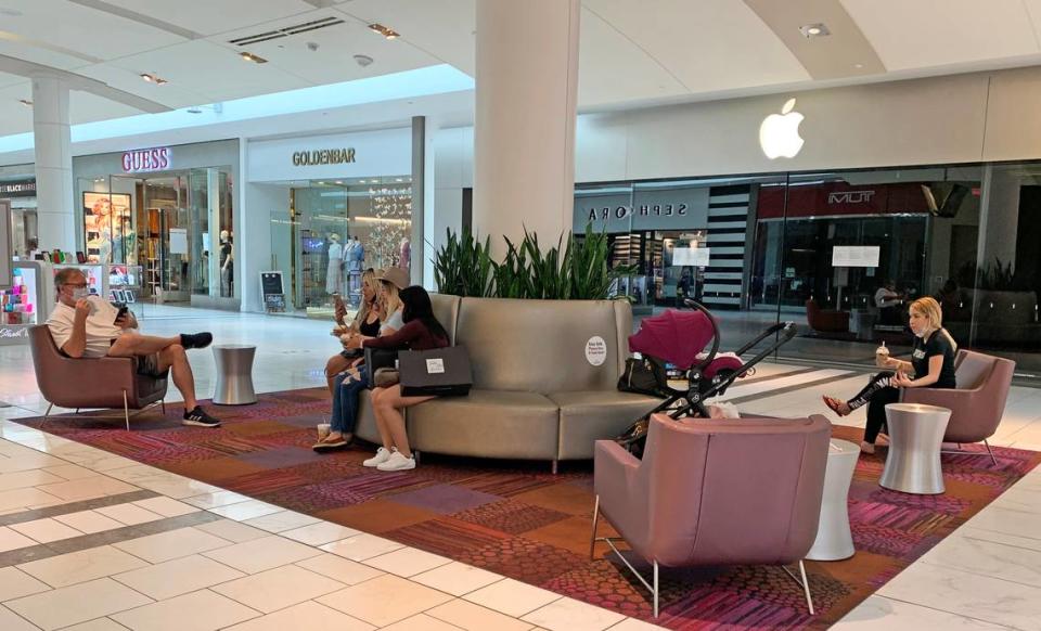 Shoppers take a break at Dadeland Mall. Some guests removed their masks to eat or drink takeout items they’d bought elsewhere in the mall.