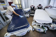 File - In this May 27, 2020, file photo, a medical worker wearing personal protective equipment cleans gurneys in the emergency department intake area at NYC Health + Hospitals Metropolitan, in New York. As coronavirus rages out of control in other parts of the U.S., New York is offering an example after taming the nation’s deadliest outbreak this spring — but also trying to prepare in case another surge comes. (AP Photo/John Minchillo, File)