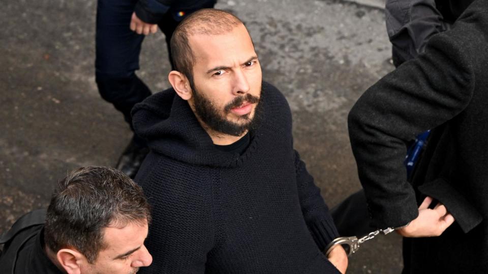 PHOTO: British-US influencer Andrew Tate arrives handcuffed and escorted by police at a courthouse in Bucharest, Romania on Feb. 1, 2023. (Daniel Mihailescu/AFP via Getty Images, FILE)