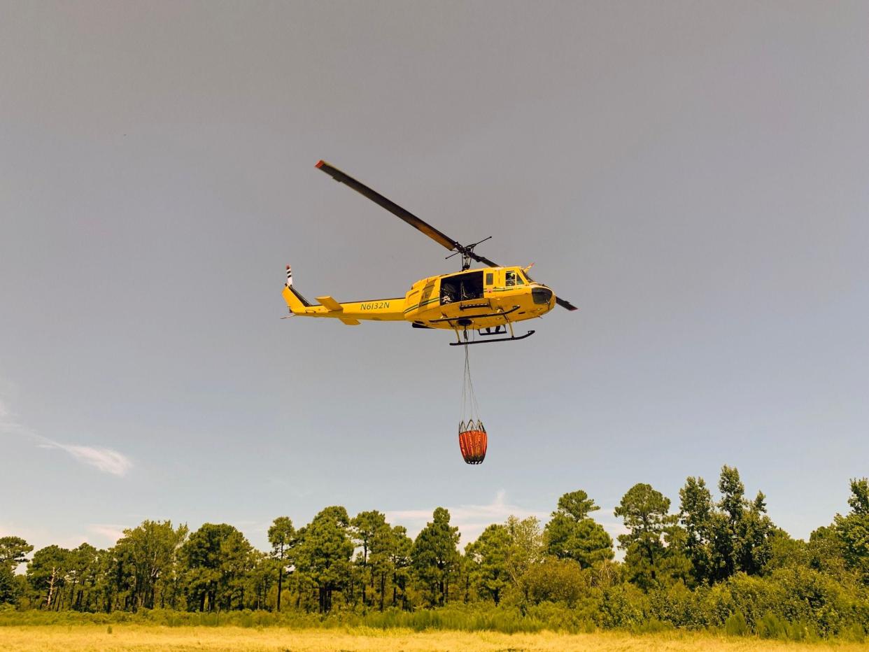 A N.C. Forest Service helicopter prepares to drop water on the smoldering "Juniper Road Two Fire" in the Holly Shelter Game Land in August 2022.