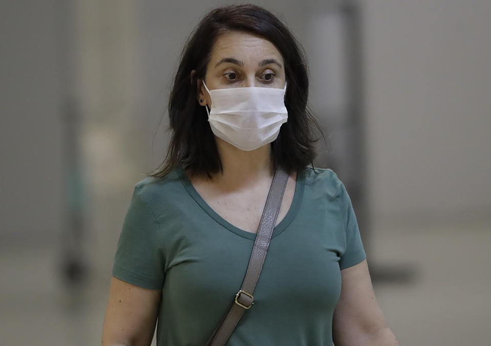 A passenger wearing a mask as a precaution against the spread of the new coronavirus COVID-19 arrives to the Sao Paulo International Airport in Sao Paulo, Brazil, Wednesday, Feb. 26, 2020. (AP Photo/Andre Penner)